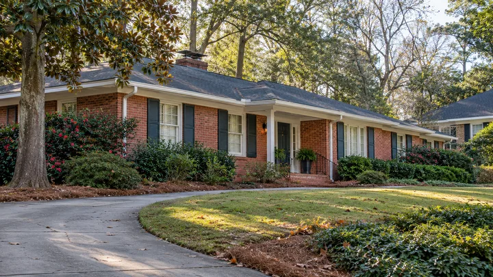 AI concept: red-brick ranch with fresh white trim from an angled driveway view